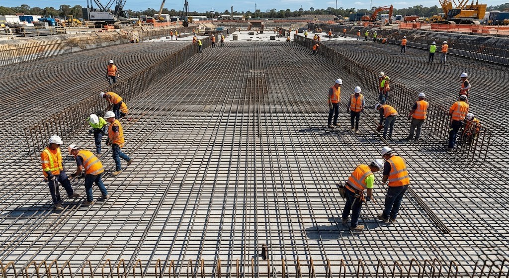 Construction workers executing a standardized rebar reinforcement method statement on a large infrastructure foundation.
