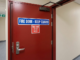 Commercial red fire door with keep closed signage and hydraulic door closer for NFPA 80 compliance